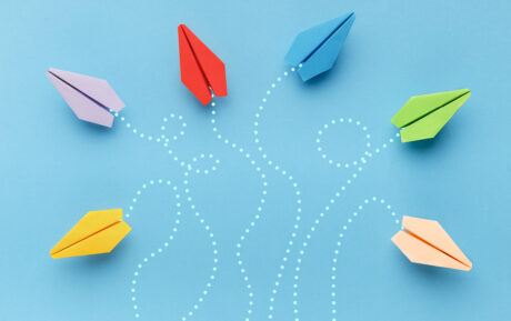 several colourful paper airplanes on different paths